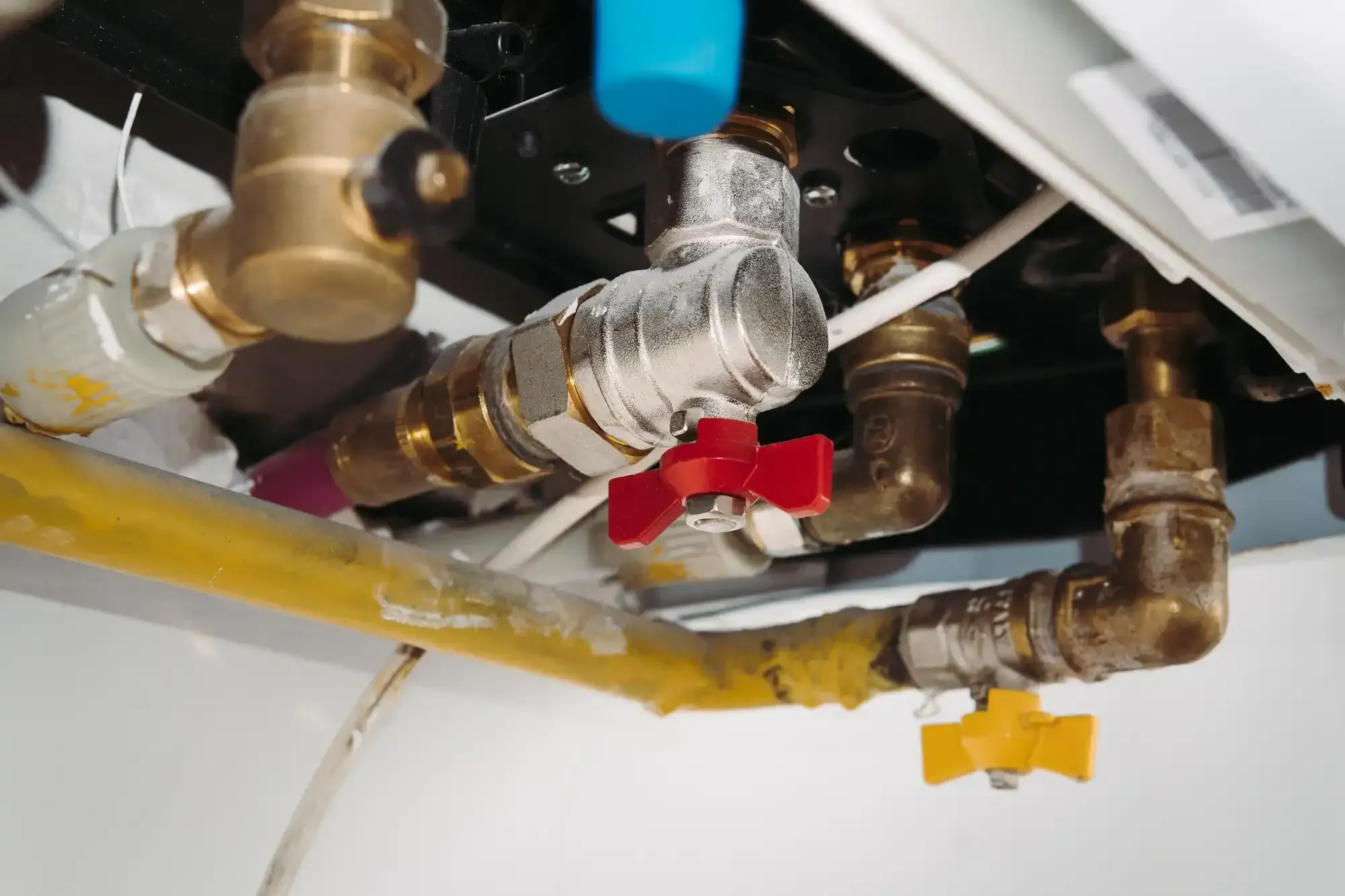 Pipes and valves in a boiler system with yellow, red, and brass components.